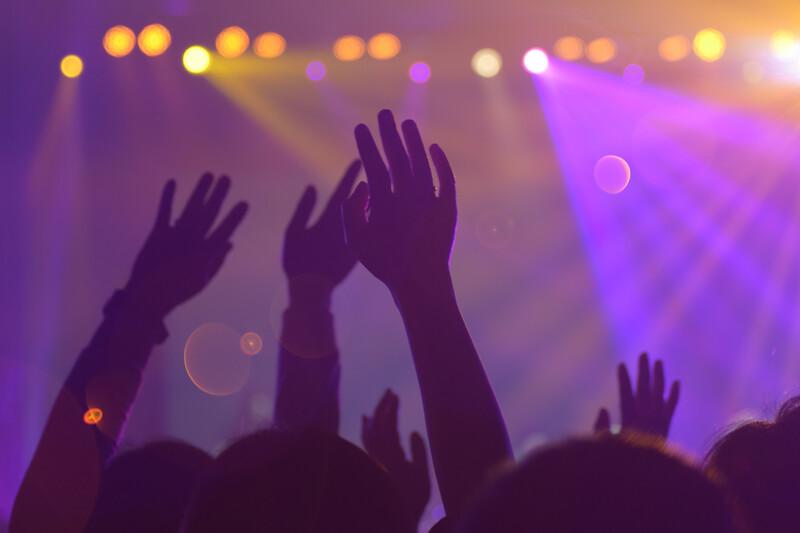 concert with lights and fans waving arms