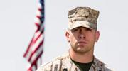 Soldier standing in front of an American flag
