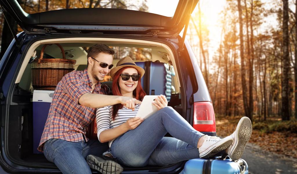 fall travel luggage in car trunk couple looking at map