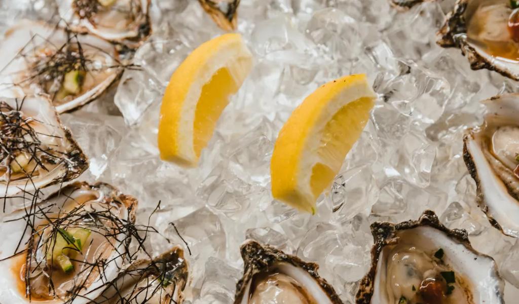 Fresh oysters on ice with lemon wedges