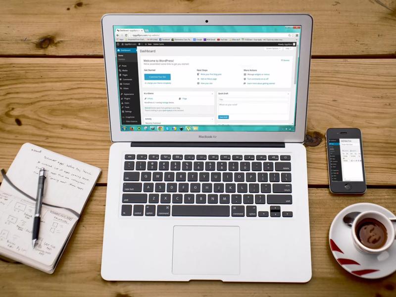 A laptop, notepad phone and coffee on a table