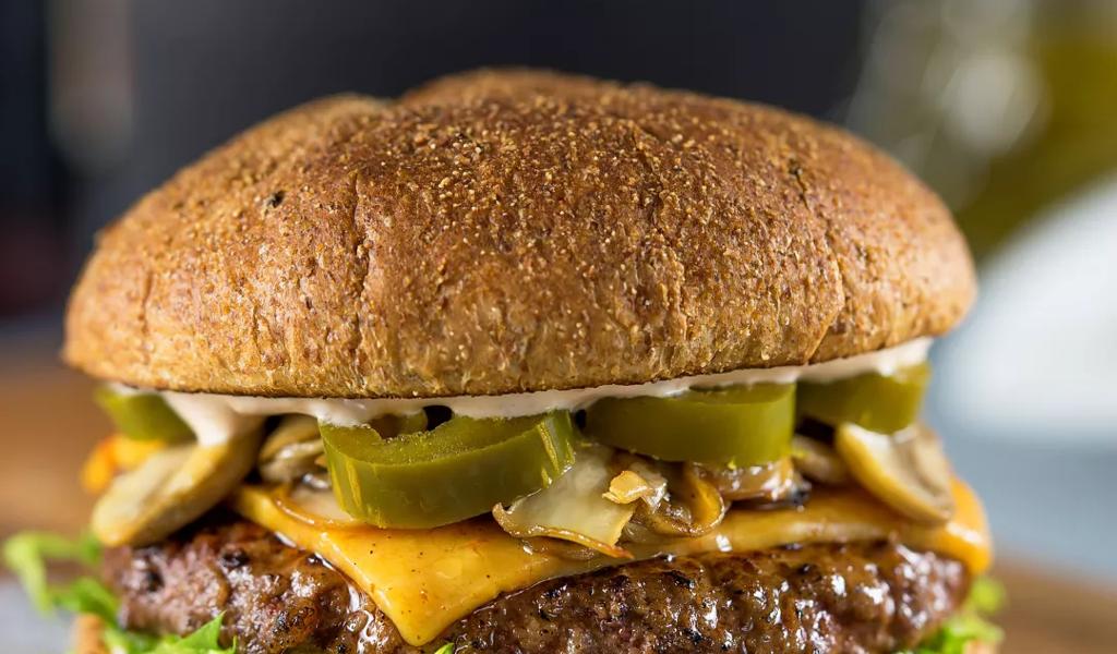 Gourmet burger with cheddar, jalapeños, and mushrooms