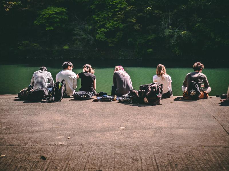 students sitting near water