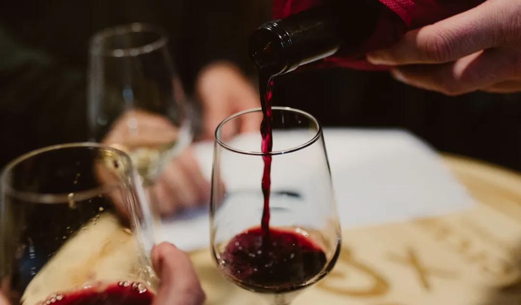 Three people sharing glasses of red wine together at Rolf and Daughters restaurant in Nashville