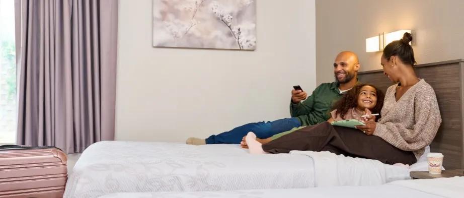 Couple with daughter on bed watching tv
